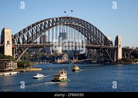 Sydney Harbour Bridge mit Luna Park im Hintergrund und Fähren Stockfoto