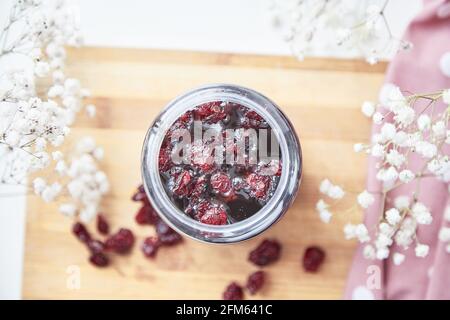 Gesundes fermentiertes Honigprodukt mit Cranberry, Probiotika. Lebensmittelkonservierungsmittel zu Hause. Köstliches Rezepturkonzept. Antivirale Lebensmittel. Draufsicht. Dekoration mit Gypsophila Blume Stockfoto