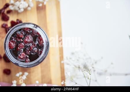 Gesundes fermentiertes Honigprodukt mit Cranberry, Probiotika. Konservierungsmittel für Lebensmittel. Köstliches Rezepturkonzept. Antivirale Lebensmittel. Draufsicht. Dekoration mit Gypsophila Blume. Speicherplatz kopieren Stockfoto