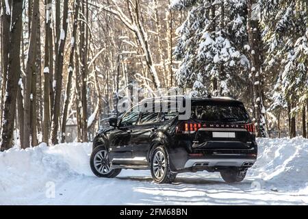 Moskau, Russland - 15. Februar 2021: Kia Mohave 2021 Black SUV im Winter im Wald geparkt. Unterwegs. Allein in den Wäldern Rückansicht. Stockfoto