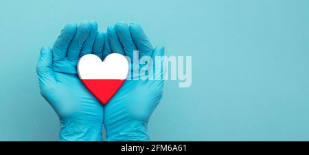 Ärzte Hände tragen chirurgische Handschuhe halten Polen Flagge Herz Stockfoto