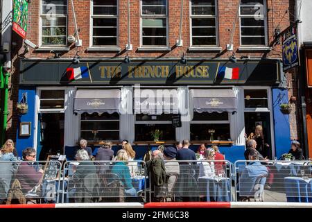 An einem sonnigen Nachmittag in London, Großbritannien, sitzen Trinker vor dem French House in Soho gesellschaftlich distanziert auf Tischen entlang des Pflasters Stockfoto