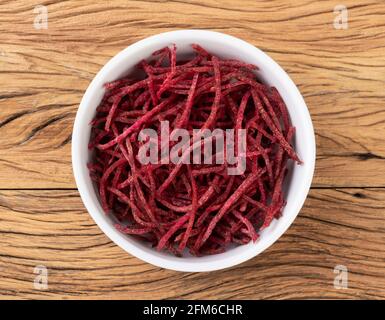 Rote Beete Streifen, im Julienne-Stil in einer Schüssel über einem Holztisch. Stockfoto