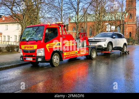 Roter Mitsubishi-Abschleppwagen von Viking Assistance Oy, der ein Auto in der Stadt schleppt. Helsinki, Finnland. 15. April 2021. Stockfoto