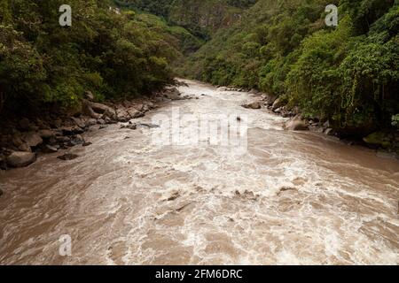 Das turbulente Wasser des Urubamba- oder Vilcanota-Flusses durchquert den Regenwald der Amazonas-Wolke, während er durch die Stadt Aguas Calientes in der Nähe von Machu Pi fließt Stockfoto