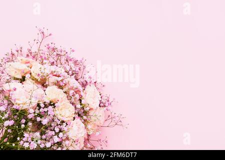 Rosa Rosen und Gypsophila Blumen Bouquet auf einem rosa Hintergrund, selektiver Fokus. Muttertag, Geburtstagsfeier Konzept. Draufsicht, Kopierbereich Stockfoto