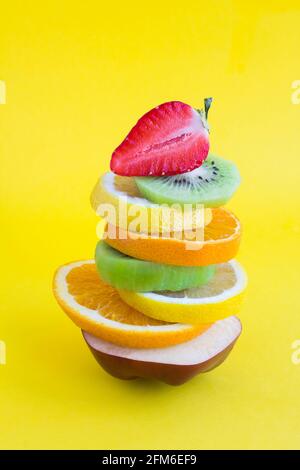 Pyramide von gehackten Früchten im Gleichgewicht auf dem gelben Hintergrund. Nahaufnahme. Stockfoto