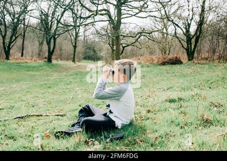 Junge, der durch ein Fernglas die Natur in der englischen Landschaft betrachtet Stockfoto