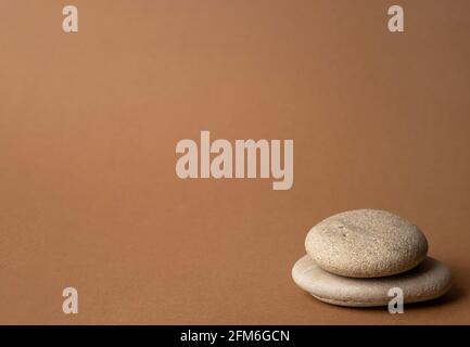 Steinkairn auf gestreiftem braunem Hintergrund, Turm aus fünf Steinen, einfache Balancesteine, Einfachheit, Harmonie und Gleichgewicht, Stein-Zen-Skulpturen Stockfoto
