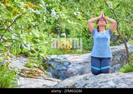 Weiße kaukasische Frau mit langen Haaren, die Yoga in der Natur praktiziert. Ruhe und Entspannung Stockfoto