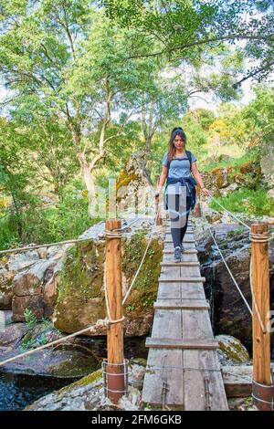 Weiße kaukasische Frau, die eine Holzbrücke in der Natur überquert Stockfoto