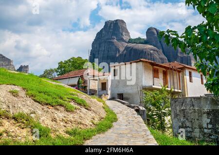 Riesige Meteora-Klippen ragen hinter Gebäuden im Dorf Kastraki. Trikala Gemeinde, Griechenland Stockfoto