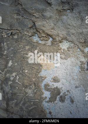 Verwitterte und rissige Betonwand mit blauem Kalk und verschiedenen Mörtelmischungen im Laufe der Zeit erhalten. Abblätternder Putz von der Oberfläche der Zementstruktur. Stockfoto