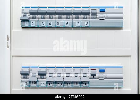 Einphasige Sicherungen und Reststromschutz in der ein- und aus-Position. Viele graue Schalter in einer Reihe, in einem Kasten in der Wand eingebaut. Stockfoto