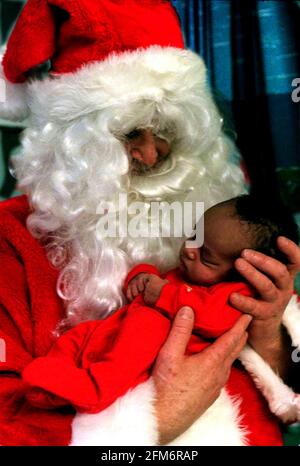 Weihnachtsbesuch des Vaters im Great Ormond Street Hospital. Bilder auf der Papageienstation (neurochirurgisch). Das Krankenhaus hatte zwei Father Christmases, die auf Tour waren; dieser ist Peter Jardine, eine Senior Staff Nurse vom Cardiac Theatre. Das Bild zeigt die 15 Tage alte Kane Williams aus Camden in London, die Ermittlungen anstellt Stockfoto