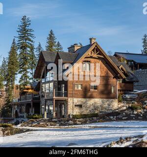 REVELSTOKE, KANADA - 16. MÄRZ 2021: Berghaus aus Holz im Wald zwischen hohen Bäumen. Stockfoto