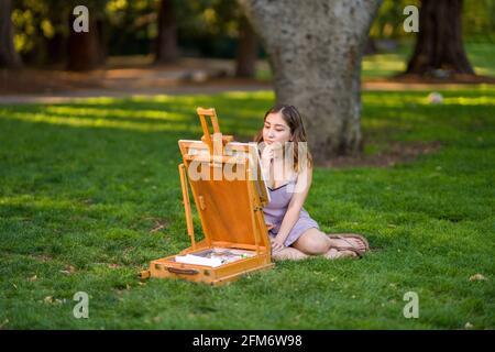 Petite junge asiatische Frau Student Malerei im Park mit Ein Kabinett-Easel Stockfoto