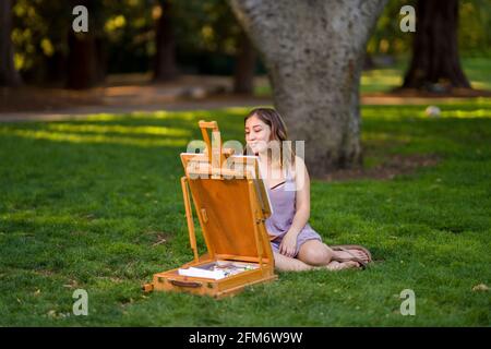 Petite junge asiatische Frau Student Malerei im Park mit Ein Kabinett-Easel Stockfoto