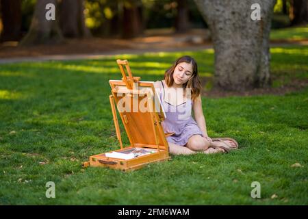 Petite junge asiatische Frau Student Malerei im Park mit Ein Kabinett-Easel Stockfoto