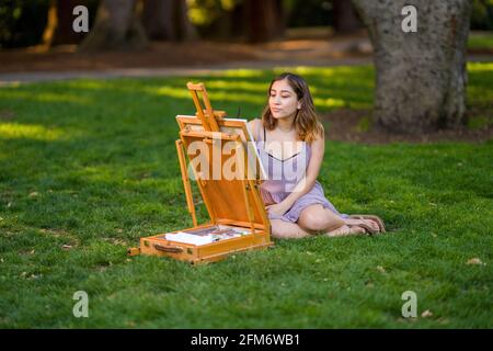 Petite junge asiatische Frau Student Malerei im Park mit Ein Kabinett-Easel Stockfoto