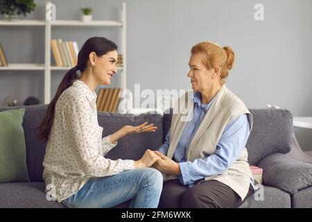 Glückliche Tochter und verständnisvoll unterstützende ältere Mutter, die auf dem Sofa sitzt Und sprechen Stockfoto