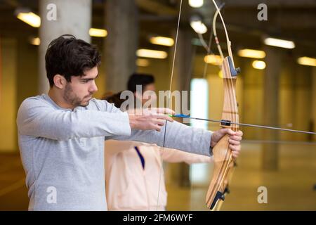 Seitenansicht eines jungen Mannes, der Bogenschießen praktiziert Stockfoto
