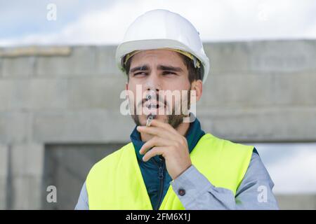 Porträt eines männlichen Baumeisters, der im Freien raucht Stockfoto