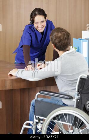 Junger Mann im Rollstuhl an der Rezeption des Krankenhauses Stockfoto