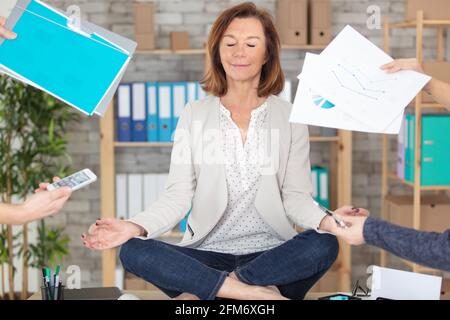 zen-reife Geschäftsfrau in Lotusposition saß auf ihrem Schreibtisch Stockfoto