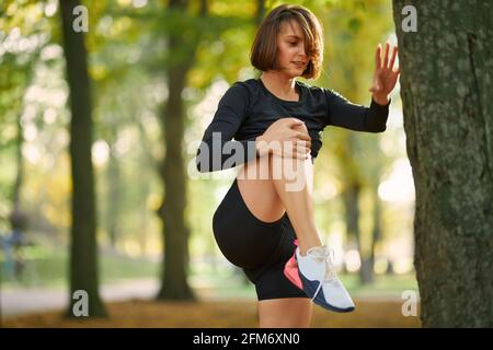 Charmante Fitness-Frau im aktiven Stretching Beine an der frischen Luft. Junge Brünette mit schlanken Körper führt aktiven und gesunden Lebensstil. Stockfoto