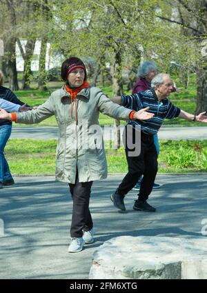 Dnepropetrovsk, Ukraine - 04.22.2021: Eine Gruppe von Senioren, die einen Gesundheits- und Fitnessgymnastikkurs in einem Park machen. Stockfoto