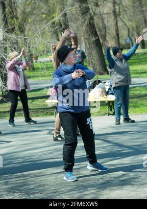 Dnepropetrovsk, Ukraine - 04.22.2021: Eine Gruppe von Senioren, die einen Gesundheits- und Fitnessgymnastikkurs in einem Park machen. Stockfoto