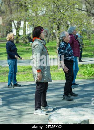 Dnepropetrovsk, Ukraine - 04.22.2021: Eine Gruppe von Senioren, die einen Gesundheits- und Fitnessgymnastikkurs in einem Park machen. Stockfoto