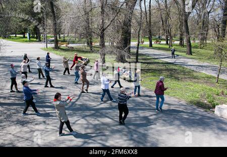 Dnepropetrovsk, Ukraine - 04.22.2021: Eine Gruppe von Senioren, die einen Gesundheits- und Fitnessgymnastikkurs in einem Park machen. Stockfoto