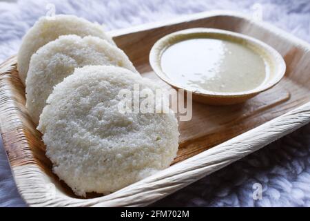 Köstliches südindisches beliebtes Frühstück Idli mit weißem Chutney auf dem Teller serviert. Stockfoto