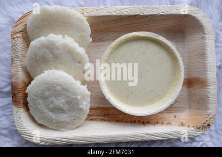 Köstliches südindisches beliebtes Frühstück Idli mit weißem Chutney auf dem Teller serviert. Stockfoto