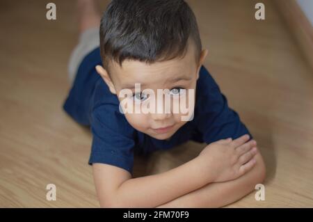 Foto eines Jungen, der mit auf dem Boden spielt Ein dunkelblaues T-Shirt Stockfoto