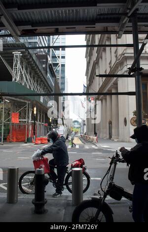 Man arbeitet für das Lebensmittelunternehmen. New Yorks Fahrräder. Der Mann fährt in Manhattan mit roten Tüten auf einem Fahrrad zur Lebensmittelzustellung. Stockfoto