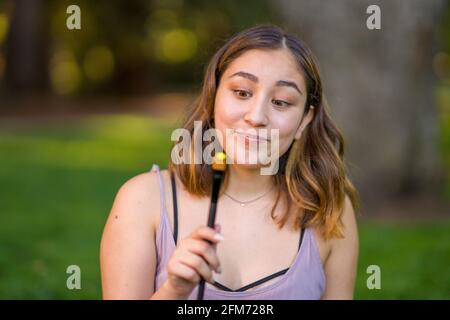 Zierlich jung asiatisch Frau Student Holding ein malen Pinsel mit Gelber Acryllack Stockfoto