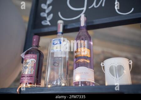 Bunte Flaschen Gin auf einem schwarzen Tisch Oder Bar mit einem Gin-Schild dahinter Stockfoto