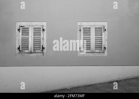 Triest, Italien. 3. Mai 2021. Zwei alte Holzfenster auf einem alten Haus, das von einer bergauf führenden Straße im Stadtzentrum aufgenommen wurde Stockfoto