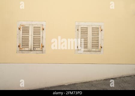 Triest, Italien. 3. Mai 2021. Zwei alte Holzfenster auf einem alten Haus, das von einer bergauf führenden Straße im Stadtzentrum aufgenommen wurde Stockfoto