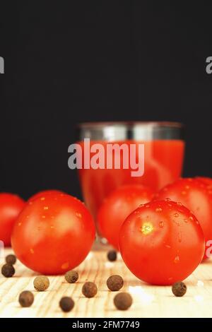 Reife rote Tomaten und Tomatensaft in einem transparenten Glas. Stockfoto