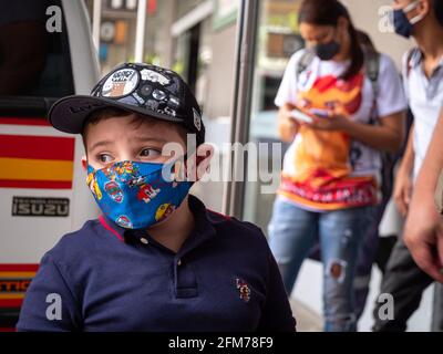 Medellin, Antioquia, Kolumbien - April 3 2021: Kleiner lateinischer Junge in Blau am Busbahnhof mit COVID Gesichtsmaske Stockfoto