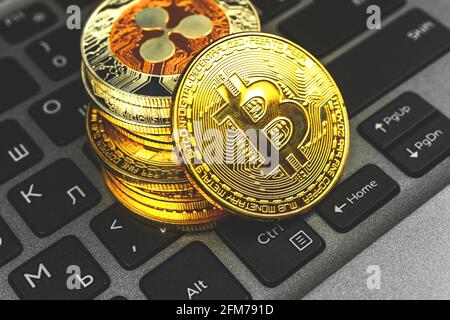Goldenes Bitcoin mit anderen Krypto-Währungsmünzen auf Laptop-Tastatur Nahaufnahme, Konzept des neuen virtuellen Geldes für Investitionen und Einsparungen Stockfoto