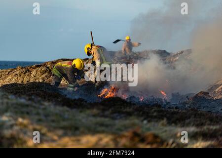 Feuerwehrmannschaften bekämpfen das Gorse-Feuer auf der Isle of Anglesey. Stockfoto