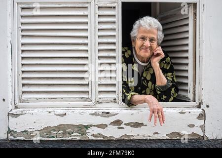 Gran Canaria, eine spanische Kanarische Insel vor der Nordwestküste von Afrika. Freundliche Seniorin im Fenster, Las Palmas. Stockfoto