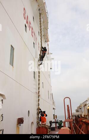 Deckcrew, die an Bord eines Frachtschiffes in der Luft arbeitet Stockfoto