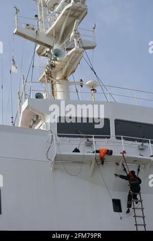Deckcrew, die an Bord eines Frachtschiffes in der Luft arbeitet Stockfoto