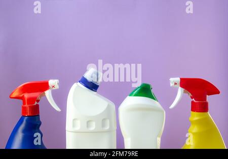 Mehrfarbige Plastikflaschen in einer Reihe mit Reinigungsprodukten auf einem lila Hintergrund. Reinigungsdienste, Kopierbereich Stockfoto